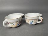 two cups with floral designs on them sitting on a table