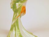 une figurine de poisson verte et orange posée sur une surface blanche