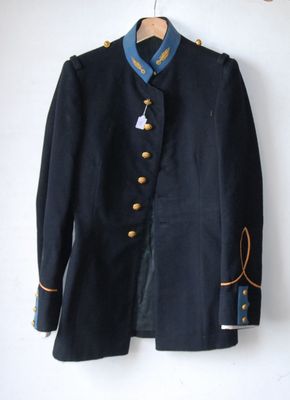 navy blue jacket with gold buttons on a hanger on a white wall