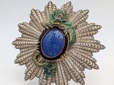 a close up of a brooch with a blue stone in the center