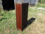 une grande armoire en bois posée dans l'herbe près d'une grange