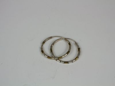 two silver and gold hoop earrings on a white surface