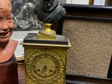 un buste d'homme assis à côté d'une horloge posée sur une table