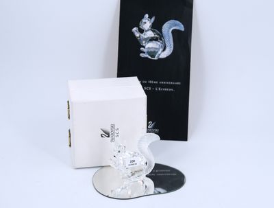 une figurine en verre représentant un écureuil assis à côté d'une boîte