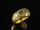 gros plan d'une bague en or avec des diamants sur une surface noire
