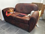 a brown leather couch with a purse and a purse on it