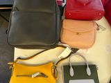 several different colored handbags are sitting on a table next to each other