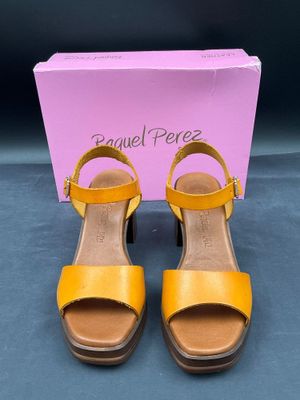 une paire de sandales jaunes devant une boîte rose