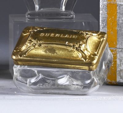 a small glass box with a gold lid next to a box with a silver lid