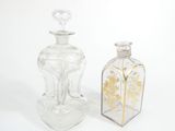 two clear glass bottles with gold designs on them sitting next to each other