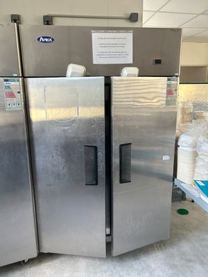 three stainless steel refrigerators in a room with a lot of boxes