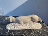 a white sculpture of a dog laying on a table