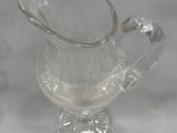 a clear glass pitcher with a handle on a table