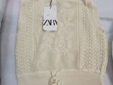 a white sweater with a tag on it next to a pair of shoes