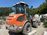an orange construction vehicle that is parked in the dirt