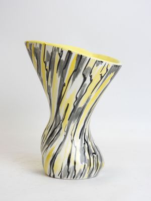 a yellow and black vase sitting on a white surface