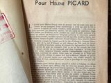 un livre ouvert posé sur une table à côté d'une feuille de papier