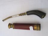 une paire de pipes anciennes en laiton et rouges posées sur un support blanc