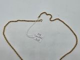 a gold chain with a tag attached to it on a white surface