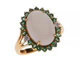 un gros plan d'une bague ornée d'une pierre blanche entourée de pierres vertes et blanches