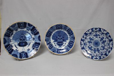 trois assiettes bleues et blanches ornées de motifs, posées à côté d'un livre