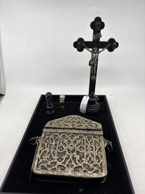 un vieux porte-monnaie en argent posé sur un plateau noir, à côté d'une croix