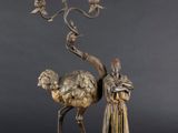sculpture en bronze représentant un homme debout à côté d'un chameau sur le dos duquel se trouve un oiseau