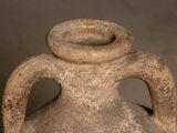 a large stone vase with a handle on a table