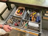 un tiroir rempli d'outils divers posé sur une table