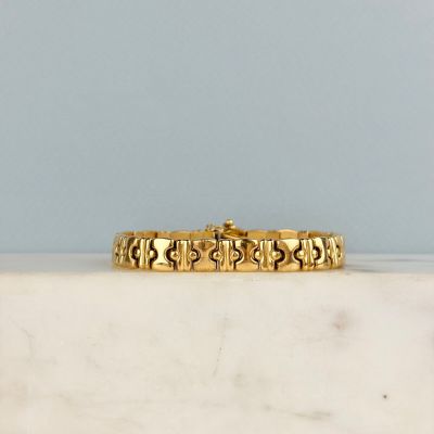 un gros plan d'un bracelet en or posé sur une surface en marbre