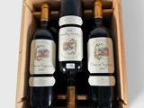 trois bouteilles de vin se trouvent dans une caisse en bois posée sur une surface blanche