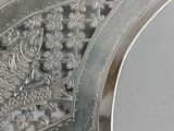 a close up of a silver plate with a bird on it