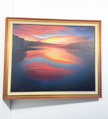 tableau accroché au mur d'une pièce où se trouve un tableau représentant un coucher de soleil