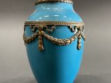 a blue vase that has a gold decoration on it