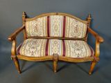 an antique wooden bench with striped upholstered seat and arms