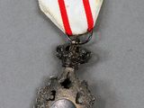 silver medal with a red and white ribbon on a gray surface