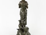 a bronze statue of a woman holding a bird on top of a rock