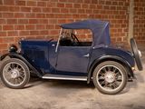 a blue vintage car parked in front of a brick wall