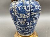 a blue and white vase on a gold stand