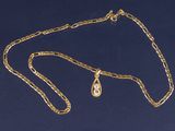 un gros plan d'un collier en or orné d'un pendentif en forme de larme