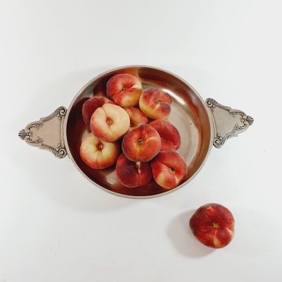 a bowl of peaches sitting on a white table