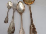 five silver spoons and two silver spoons on a table