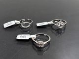 trois bagues en diamant posées sur un fond noir, accompagnées d'une étiquette de prix