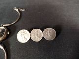 three coins sitting next to a watch on a table