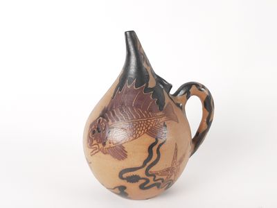un petit vase orné d'un poisson, posé sur un fond blanc