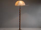 un lampadaire en bois surmonté d'un abat-jour blanc