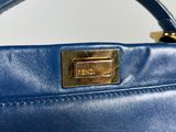 the handle of a blue handbag with a gold plate on it