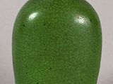a green vase with a lid sitting on a table