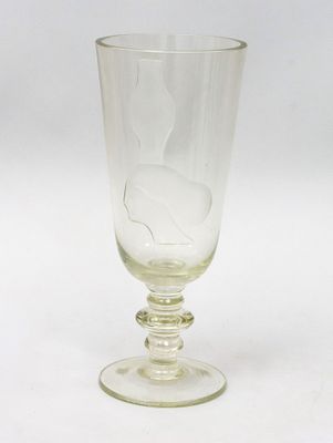 un verre sur lequel repose une feuille, posé sur une table