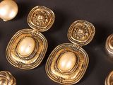 some gold and pearl earrings are sitting on a black surface